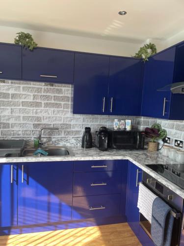 una cocina con armarios azules y fregadero en THE PAISLEY PENTHOUSE - ABBEY VIEW, en Paisley