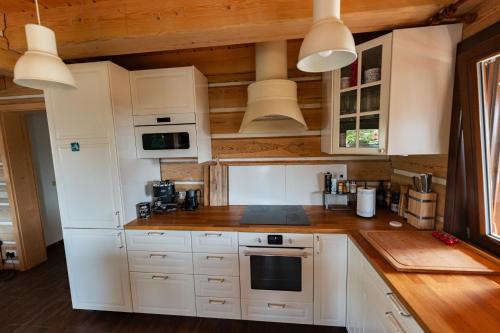 a kitchen with white cabinets and white appliances at Moderní šumavská roubenka s výhledem na Boubín in Vimperk