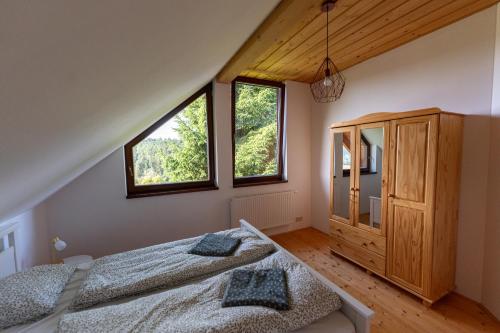 1 dormitorio con 2 camas y 2 ventanas en Moderní šumavská roubenka s výhledem na Boubín, en Vimperk