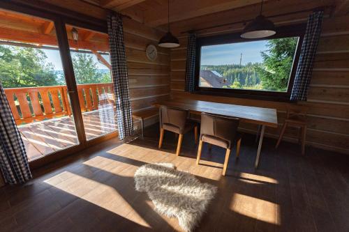 a dining room with a table and chairs in a cabin at Moderní šumavská roubenka s výhledem na Boubín in Vimperk