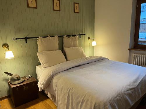 a bedroom with a large bed with white sheets and pillows at Casa Pura in Ampezzo