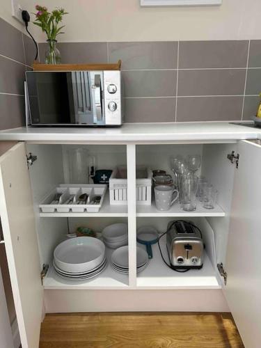 a kitchen cabinet with a microwave and plates at Leafy lodge in Lytham in Brown Moss Side