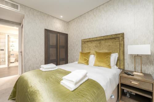 a bedroom with a large bed with white sheets and gold pillows at Chancery Lane by Capital in London