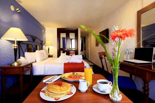 una habitación de hotel con una mesa con crepes y una cama en Hotel Emily en Pachuca de Soto