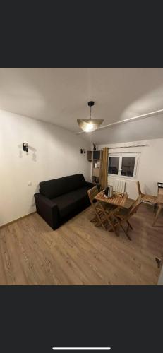 un salon avec un canapé noir et une table dans l'établissement Chambre 7 kitchenette Les gites de la Gare, à Mussidan