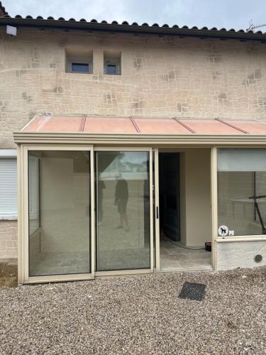 a conservatory with sliding glass doors in front of a building at Chambre 7 kitchenette Les gites de la Gare in Mussidan
