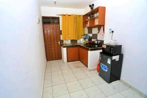 - une cuisine avec des placards en bois et un petit réfrigérateur dans l'établissement Lux Suites Ratna Furnished Apartments, à Mombasa
