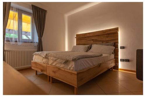 - une chambre avec un grand lit en bois et une fenêtre dans l'établissement appartamento Bait del Gioti, à Tiarno di Sotto