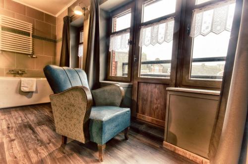 La salle de bains est pourvue d'une chaise bleue et de fenêtres. dans l'établissement Café René Borgloon, à Looz