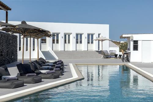 a pool with chaise lounges and chairs next to a building at Secret View Hotel in Oia