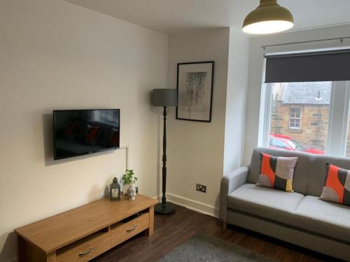 - un salon avec un canapé et une télévision dans l'établissement Drummond Condo, à Édimbourg