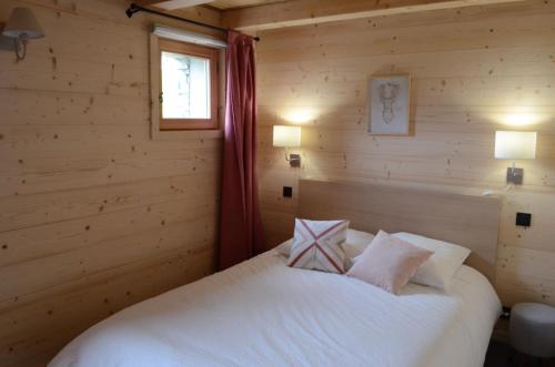 - une chambre avec un lit blanc dans une cabane en rondins dans l'établissement Appartement Les Greniers Châtel Réservation, à Châtel