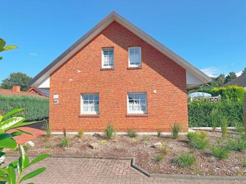 a red brick house with white windows and a yard at Ferienhaus am See in Haselünne