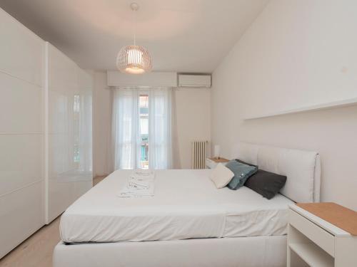 ein weißes Schlafzimmer mit einem großen Bett und einem Kronleuchter in der Unterkunft Youhosty - Grazioli 4 in Mailand