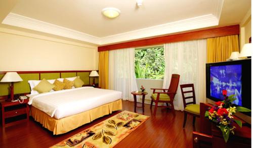 a bedroom with a bed and a flat screen tv at Kalim Resort in Patong Beach
