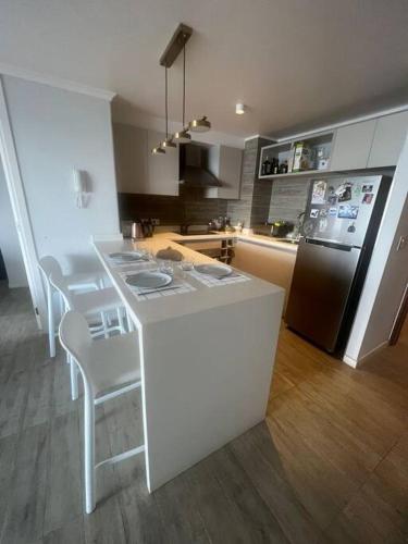 a kitchen with a white counter and a refrigerator at Junto al mar Concon in Concón