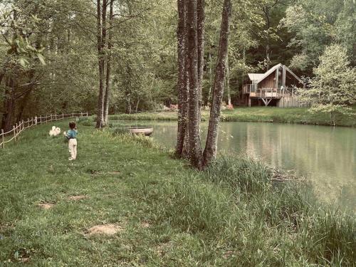 Ein kleiner Junge stand im Gras neben einem See in der Unterkunft Casa Slow avec sa piscine chauffée au bord du lac in Les Croix Chemins