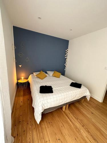 - une chambre avec un lit et un mur bleu dans l'établissement Appartement T3 cosy et moderne, à Baugé