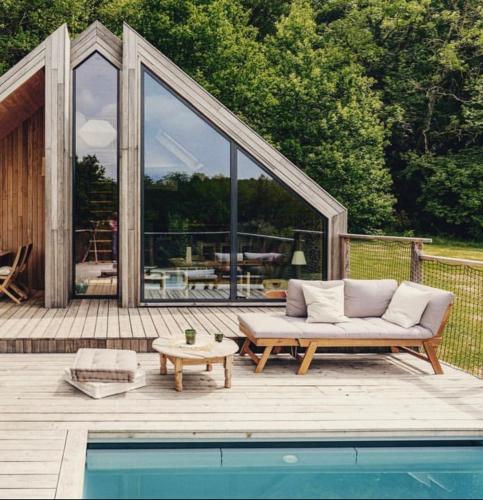 - un canapé installé sur une terrasse à côté de la piscine dans l'établissement Casa Slow avec sa piscine chauffée au bord du lac, à Les Croix Chemins