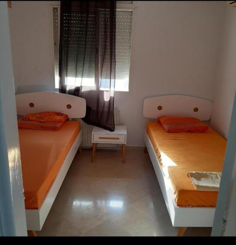 two beds in a small room with a window at Corniche in Mahdia