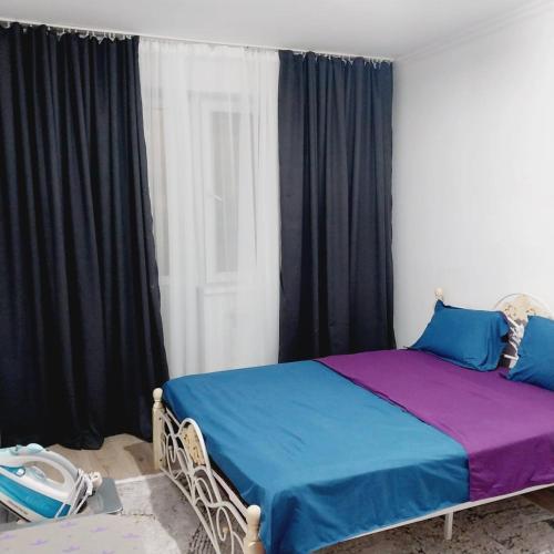een slaapkamer met een bed met blauwe en paarse lakens bij жк Утеген in Alma-Ata