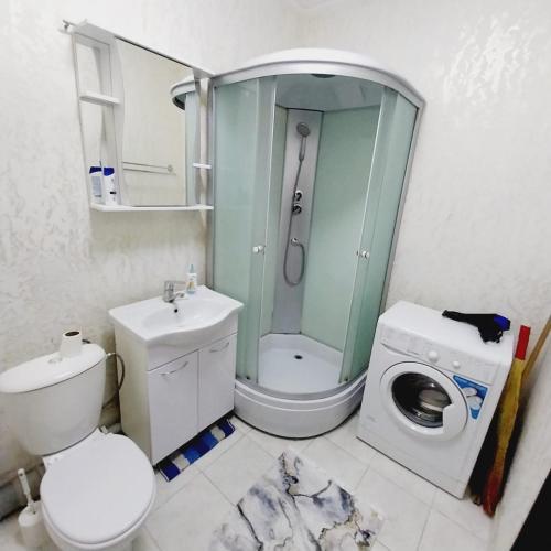 een badkamer met een douche, een toilet en een wasmachine bij жк Утеген in Alma-Ata