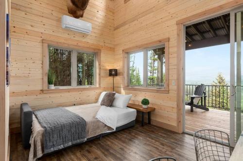 a bedroom with a bed and a balcony with windows at One of a kind views of GNP - Cabin 2 in Polebridge
