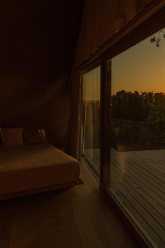 a bedroom with a bed and a large window at Cabañas de Xarás - Margarida in Marín