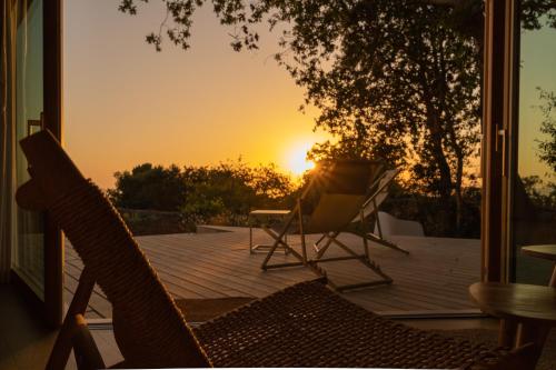 a patio with two chairs and the sunset in the background at Cabañas de Xarás - Margarida in Marín