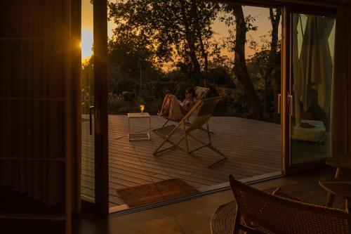 a woman sitting in a chair on a wooden deck at Cabañas de Xarás - Margarida in Marín