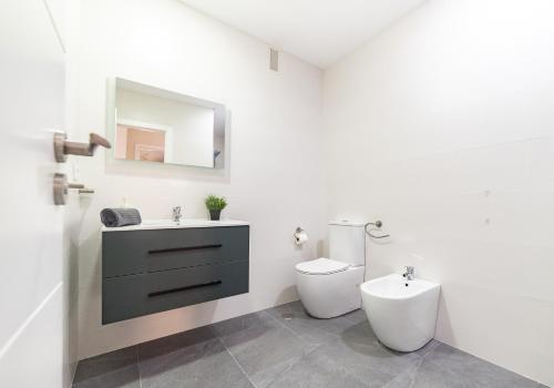 a white bathroom with a toilet and a sink at Apartamento Plaza da Gándara in Narón