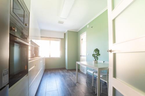 a kitchen with green walls and a table and a window at Apartamento Plaza da Gándara in Narón