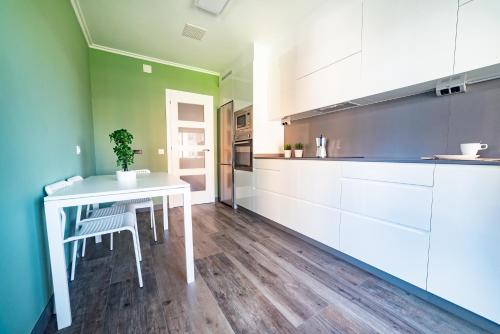 a kitchen with white cabinets and a table with a potted plant at Apartamento Plaza da Gándara in Narón