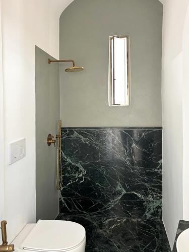 a bathroom with a toilet and a black marble wall at Roiss Haus Suites in Lecce