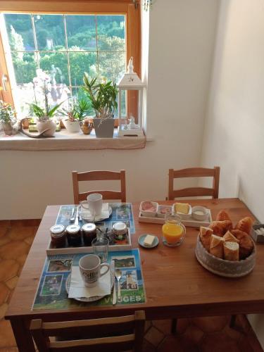 a wooden table with a breakfast of bread and orange juice at Les Sapins in Bussang