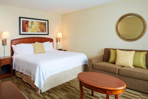 a hotel room with a bed and a couch at Courtyard Boston Woburn/Boston North in Woburn
