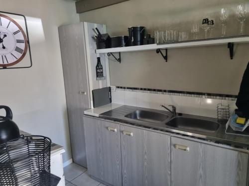 eine Küche mit einem Waschbecken und einer Uhr an der Wand in der Unterkunft Angel 8 AirBnB Apartment 2 in Robertson