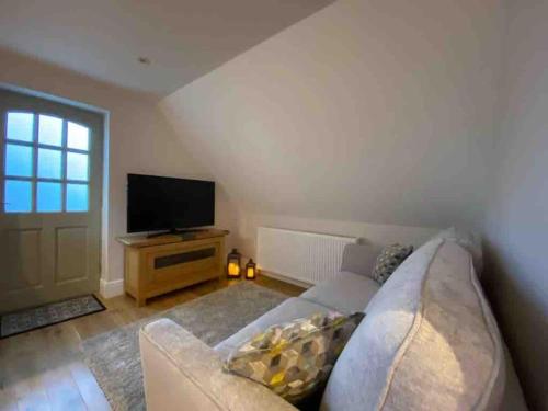 a living room with a couch and a flat screen tv at The Cotswold Stowaway, Perfect Luxurious Retreat! in Stow on the Wold