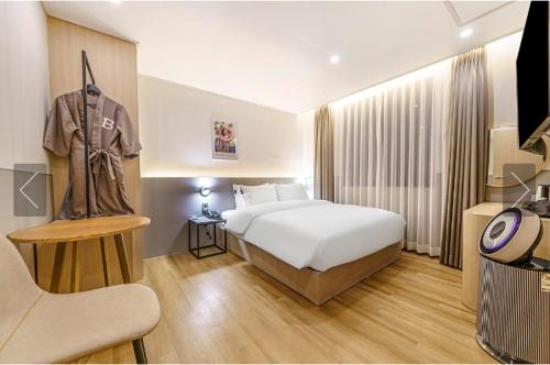 una habitación de hotel con una cama y una camisa colgada en la pared en Brown Dot Hotel Yeonsan en Busan