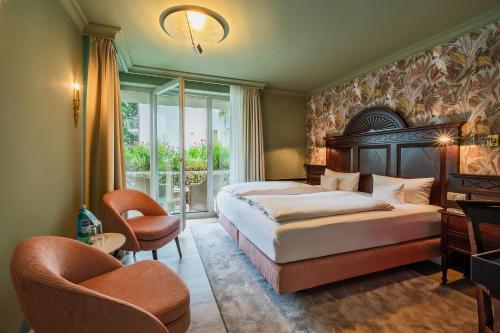 a bedroom with a bed and chairs and a window at Strandhotel Heringsdorf in Heringsdorf