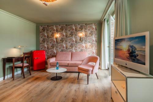 a living room with a pink couch and a tv at Strandhotel Heringsdorf in Heringsdorf