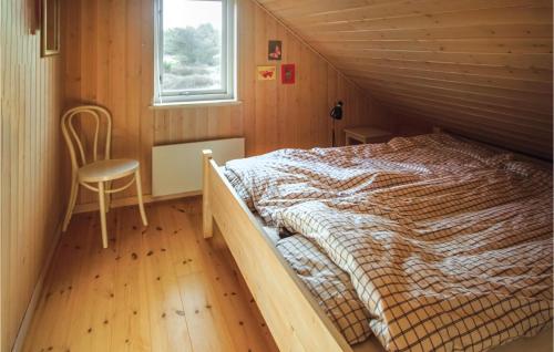 Sønder VorupørにあるBeautiful Home In Thisted With 3 Bedrooms, Sauna And Wifiの窓と椅子が備わる木造の部屋のベッド1台分です。