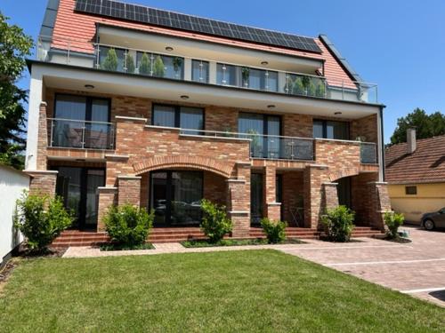 a large brick house with solar panels on it at Castellum Apartmanház in Gyula