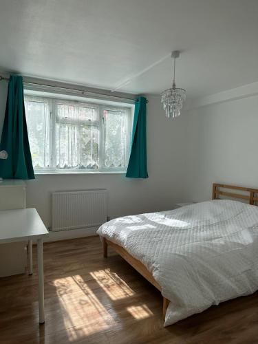 a bedroom with a bed with green curtains and a chandelier at Spacious 2 bed flat (Free WiFi) Free Parking in Barking