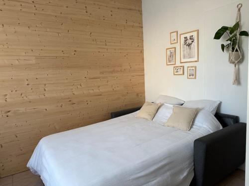 - une chambre avec un lit blanc et un mur en bois dans l'établissement Appartement lumineux Parking Privé Gratuit, à Bourg-en-Bresse