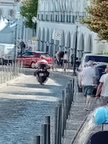 a person riding a motor bike down a street with at T1 N 93 Ref 001 in Tavira