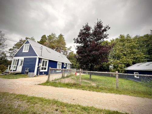 una casa azul con una valla al lado de un campo en Cottage Retreat on 11 Acres, en Flesherton