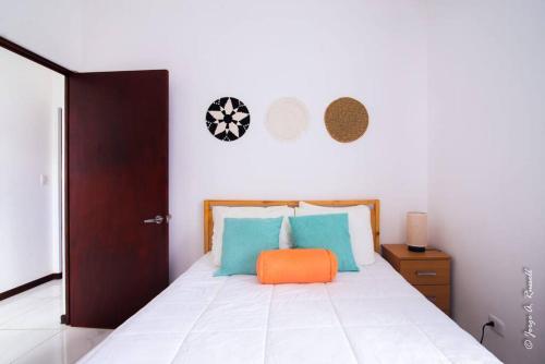 a bedroom with a bed with an orange pillow on it at Natural Arenas 47 ! in Herradura