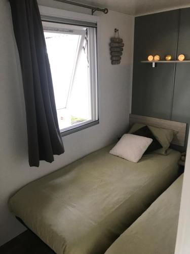 a small bed in a room with a window at Chaussy55 in Lagorce