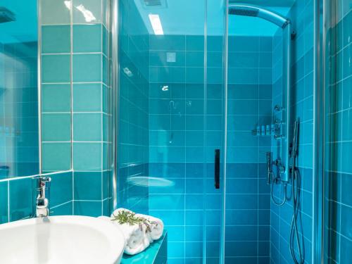 uma casa de banho em azulejos azuis com um lavatório e um chuveiro em Paradise Design Apartments em Batsi